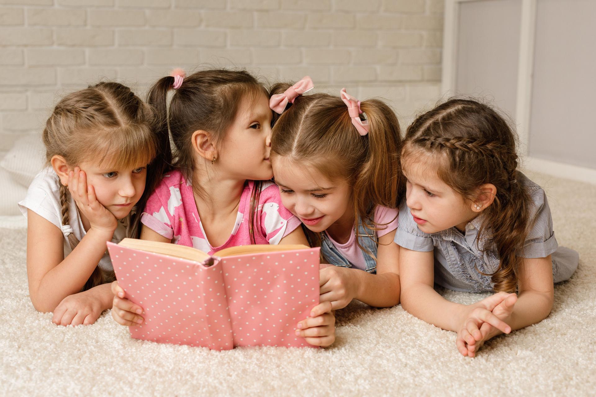 Grupo de crianças deitada no chão e lendo livro de contos
