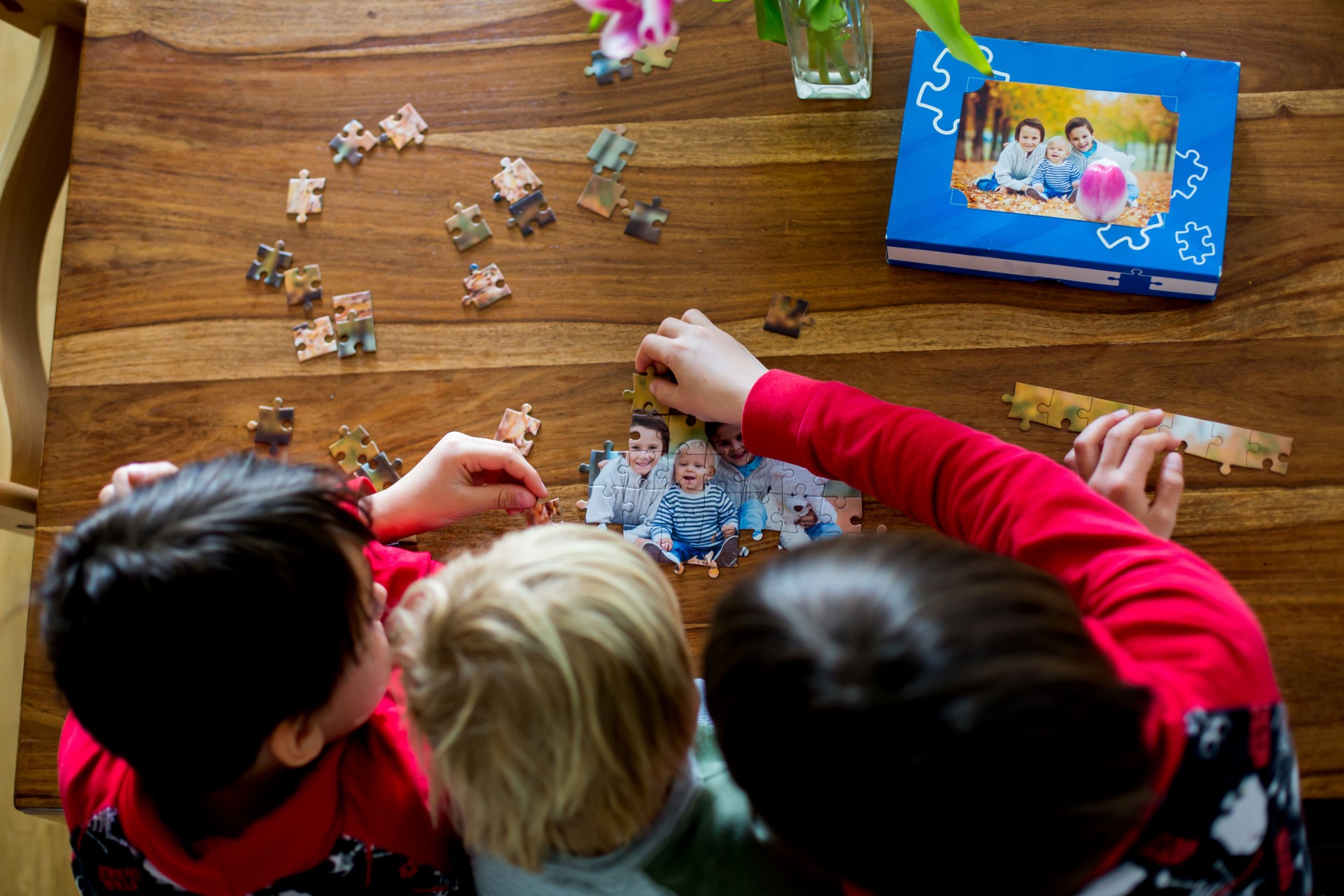 Três crianças, meninos, montando quebra-cabeça com sua imagem de uma floresta de outono, brincando em casa
